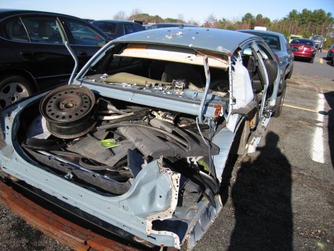 2001 Ford Crown Victoria - This heavily damaged 2001 Ford Crown Victoria shows significant rear-end destruction and is filled with various automotive parts.