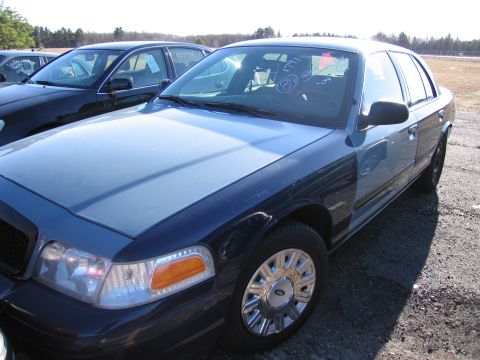 2001 Ford Crown Victoria - A blue 2001 Ford Crown Victoria is parked in an outdoor lot next to another vehicle.