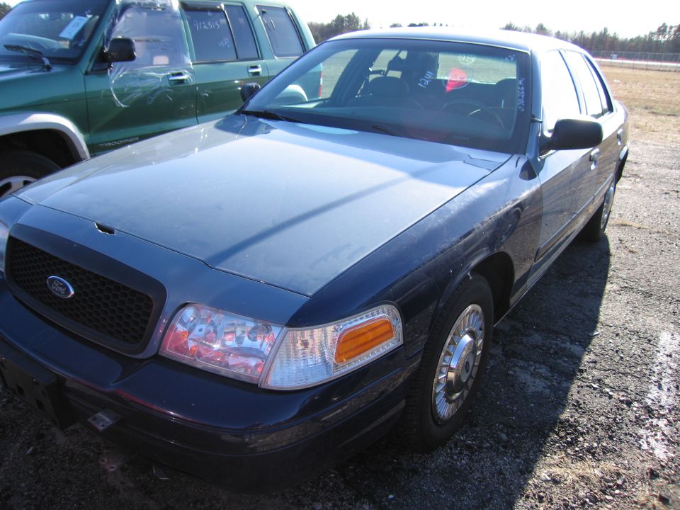 Dark blue and gray 2001 Ford Crown Victoria, front passenger side, parked on gravel lot