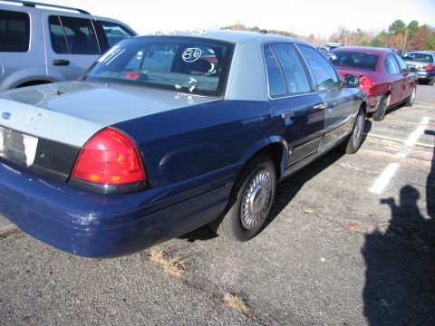 2001 Ford Crown Victoria - A two-tone Ford Crown Victoria is parked in a lot with other vehicles visible.