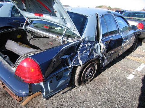 2001 Ford Crown Victoria - This sedan has extensive damage to its rear passenger side, with the trunk open.