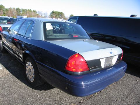 2001 Ford Crown Victoria - The rear of a two-tone 2001 Ford Crown Victoria is visible, parked in an outdoor lot.