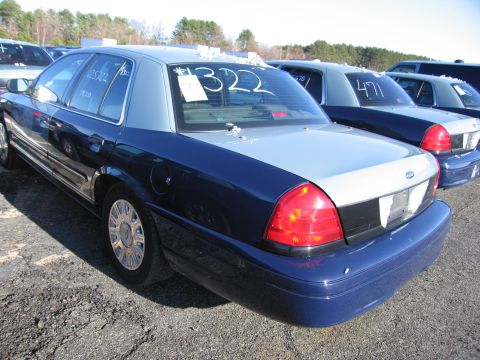 2001 Ford Crown Victoria - Several Ford Crown Victorias are lined up in an outdoor lot, with the closest one showing its rear and side profile.