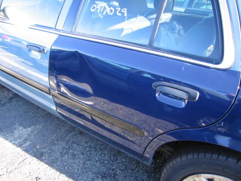 2001 Ford Crown Victoria - Dented rear door on a 2001 Ford Crown Victoria, with a two-tone paint scheme.