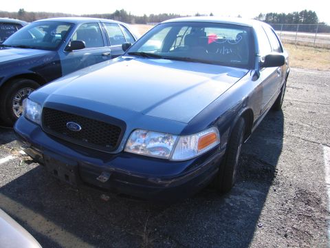 2001 Ford Crown Victoria - A blue Ford Crown Victoria is parked in an outdoor lot next to another vehicle.
