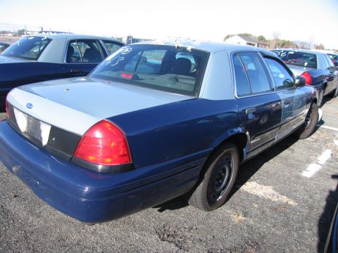 2001 Ford Crown Victoria - A two-tone Ford Crown Victoria is parked in a lot with other vehicles.