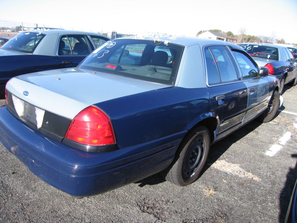 Blue and silver Ford Crown Victoria, rear quarter view, showing damage on the roof
