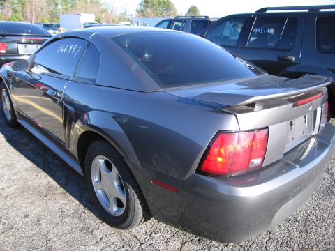 2001 Ford Crown Victoria - A gray Ford Mustang is parked in a lot with other vehicles. White numbers are written on the driver's side window.