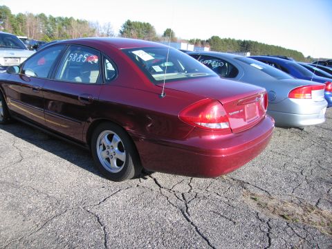 2001 Ford Crown Victoria - A red sedan is parked in a lot with other vehicles. A sticker with the number 5885 is visible on the rear window.