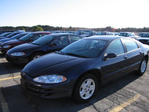2001 Ford Crown Victoria - A dark blue sedan is parked in a lot with many other vehicles under a clear sky.