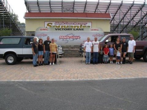 1995 Ford Bronco - Families pose with their vehicles in front of the victory lane at Maple Grove Raceway.