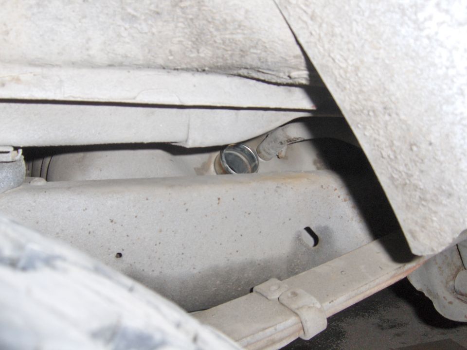 Underside chassis view showing transmission housing with metal plug and leaf spring