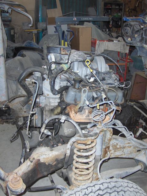 1990 Ford Bronco - Engine and suspension components are visible in a cluttered garage setting.