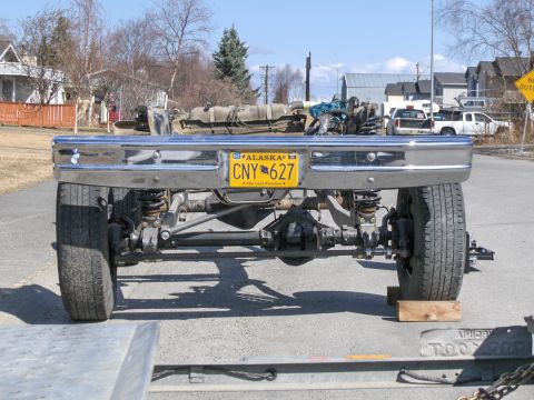 1990 Ford Bronco - Rear axle and suspension assembly with Alaska license plate CNY 627 is visible, with other vehicles in the background.