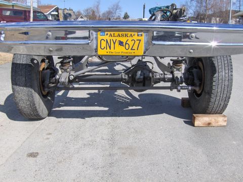 1990 Ford Bronco - Close-up view of the rear axle and suspension system, an Alaska license plate.