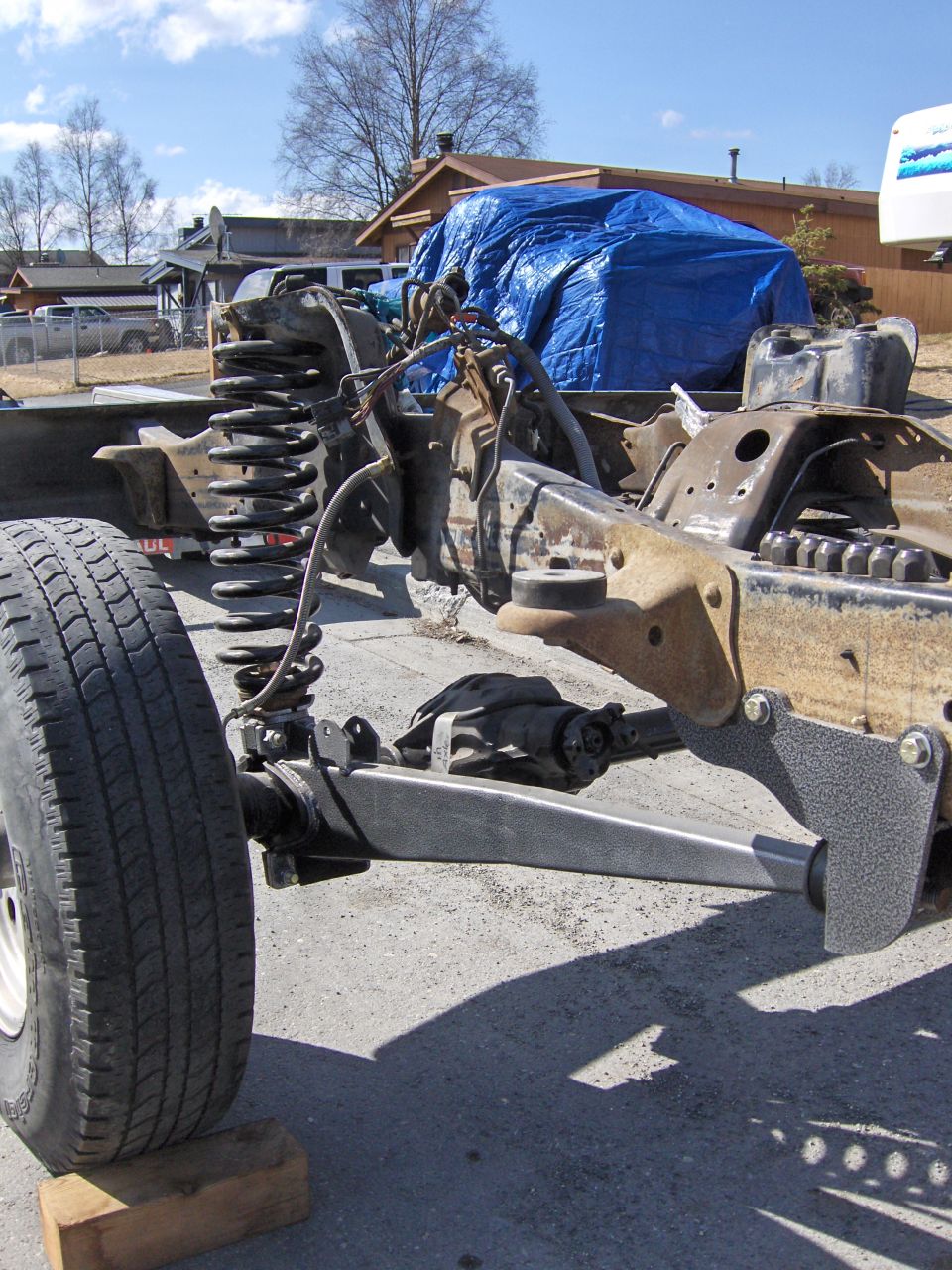 Bare truck frame with front coil suspension and axle exposed, body removed