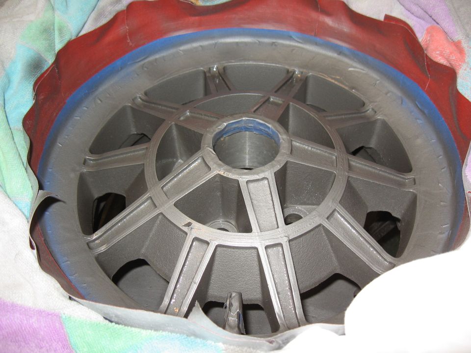 Gray painted wheel with taped red and blue rim on a colorful cloth.