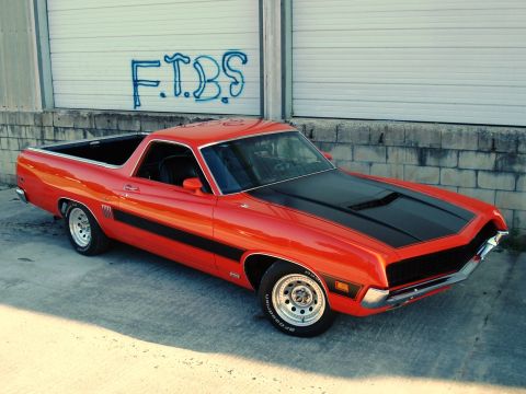 1970 Ford Ranchero - Red 1970 Ford Ranchero parked in front of a garage door with graffiti.