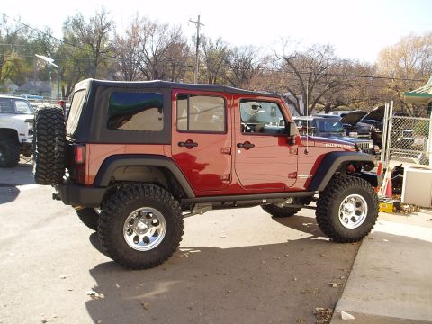 1978 Ford Bronco - This lifted red Jeep Wrangler Rubicon is shown from the side, large off-road tires and a soft top.