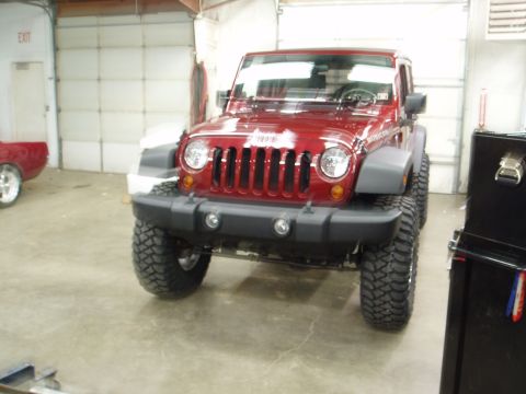 1978 Ford Bronco - A red Jeep Wrangler is shown from the front in a garage setting, aftermarket modifications.