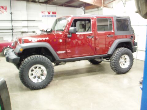 1978 Ford Bronco - A red Jeep Wrangler is shown with its doors and soft top on, lifted for off-road use.