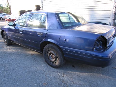 1991 Ford LTD Crown Victoria - Rear view of a blue sedan with damaged rear end, parked outdoors.