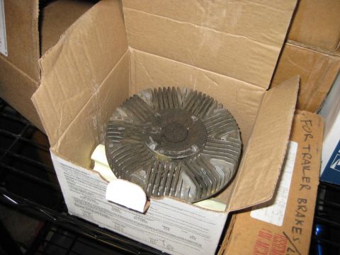 1995 Ford Bronco - A radiator fan clutch is shown inside a cardboard box, surrounded by other shipping containers.