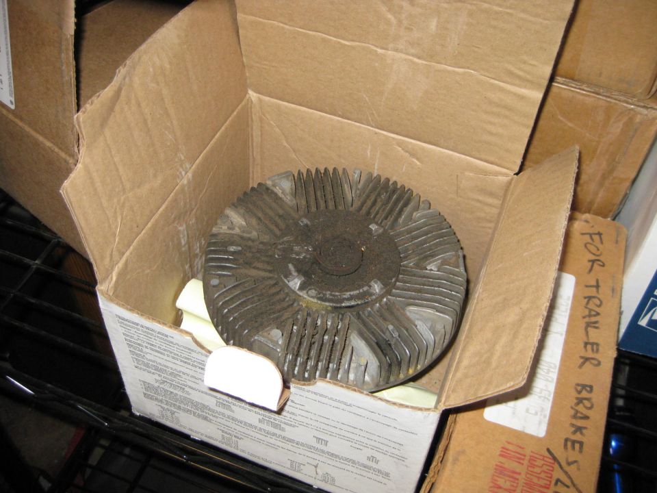 Fan clutch in a cardboard box, next to other boxes. One box is labeled 'FOR TRAILER BRAKE'