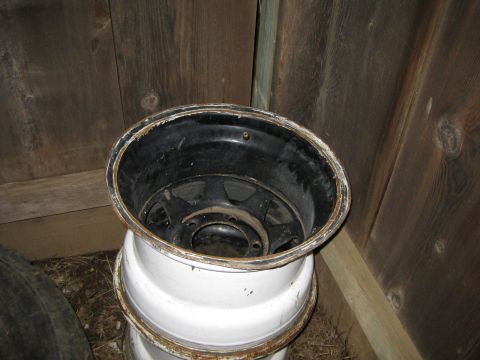 1995 Ford Bronco - Two old rims are shown stacked against a wooden wall.