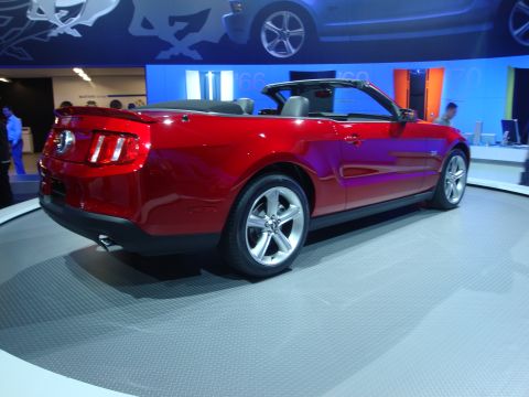 1993 Ford Taurus - A red convertible sports car is displayed on a rotating platform at an auto show.