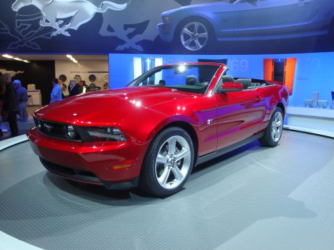 1993 Ford Taurus - A red convertible is displayed at an auto show with a blue car in the background.
