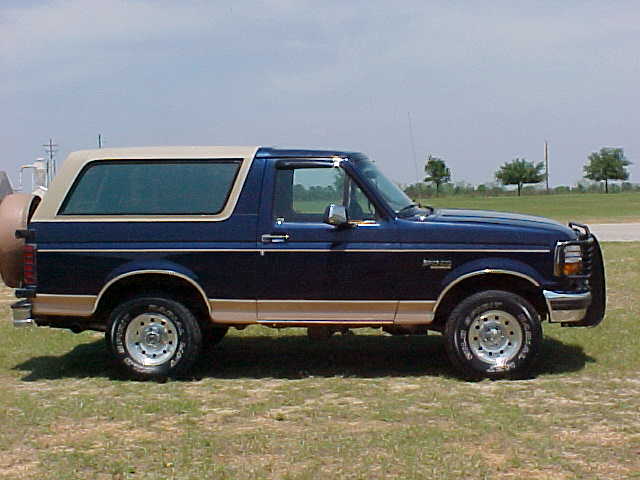 Blue and tan Ford Bronco SUV in side profile parked on grass