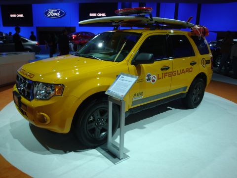 1993 Ford Taurus - This yellow Ford SUV, equipped for lifeguard duty, is displayed indoors with surfboards on its roof rack.