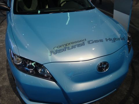 1993 Ford Taurus - A blue car with 'compressed Natural Gas Hybrid' text is displayed at an auto show.