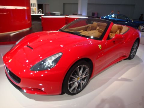 1993 Ford Taurus - A bright red convertible sports car is displayed indoors, with a blue car in the background.