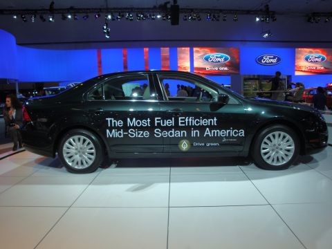 1993 Ford Taurus - A dark green sedan is displayed at an auto show with text on its side promoting fuel efficiency.