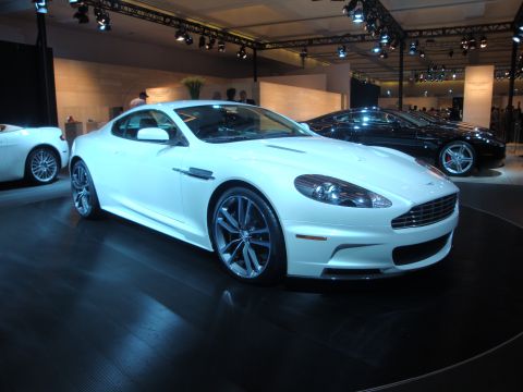 1993 Ford Taurus - A white sports car is showcased at an auto show, with another vehicle visible in the background.