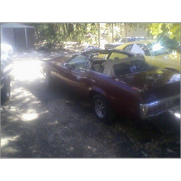 maroon convertible parked outside, another yellow car behind it