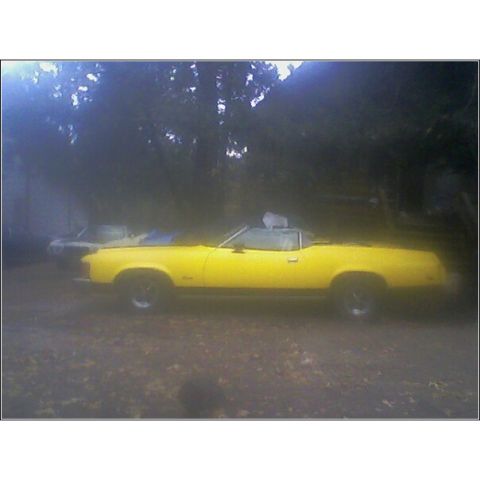 1973 Mercury Cougar - A yellow convertible is parked outdoors with another vehicle partially visible behind it.