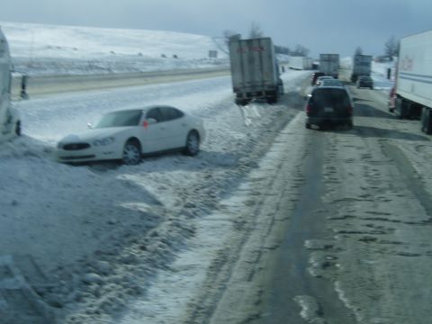 1995 Mercury Grand Marquis - Multiple vehicles, including a white sedan, are on a snow-covered highway during winter conditions.