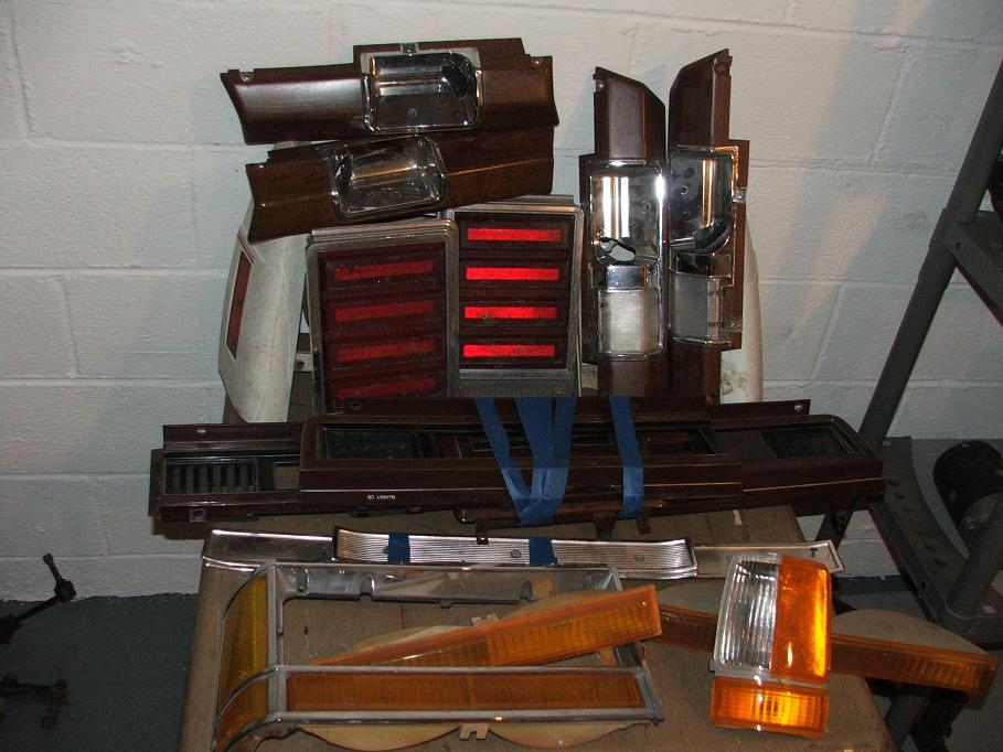Collection of car tail lights, turn signals, and trim pieces, some with woodgrain accents