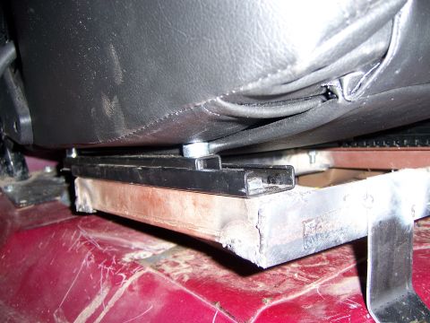 1991 Ford Bronco - Close-up view of a seat bracket assembly, showing the mounting hardware and the underside of a black leather seat.