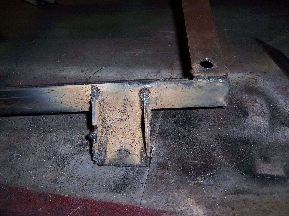 Welded metal seat bracket with holes, showing rust and wear