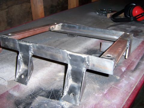1991 Ford Bronco - Custom fabricated metal bracket, likely for automotive use, sits on a work surface.