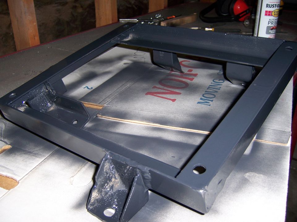 Gray metal seat bracket on a cardboard box with text