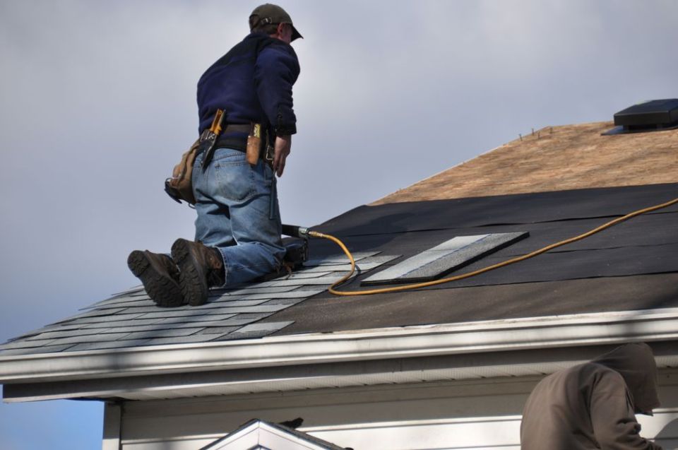 Worker on a roof using a nail gun during repairs