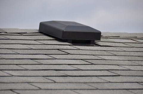 1996 Ford Bronco - A black plastic roof vent is installed on a gray asphalt shingle roof under a cloudy sky.