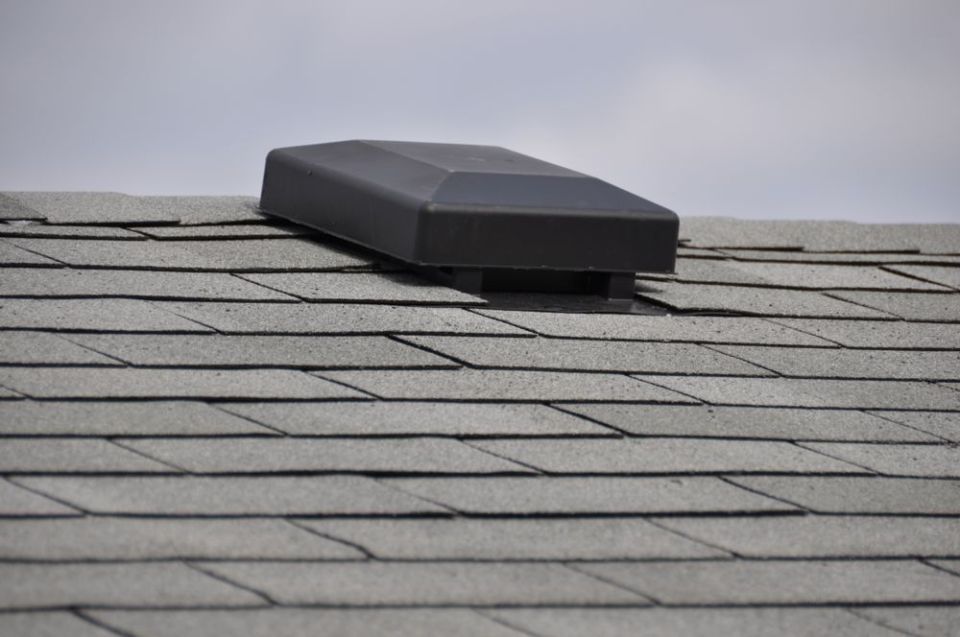 Black plastic roof vent on gray asphalt shingles
