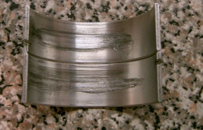 Worn engine bearing with visible scoring and damage
