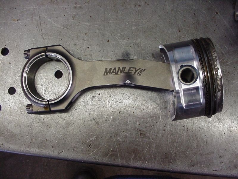 Manley connecting rod attached to a piston, resting on a metal workbench